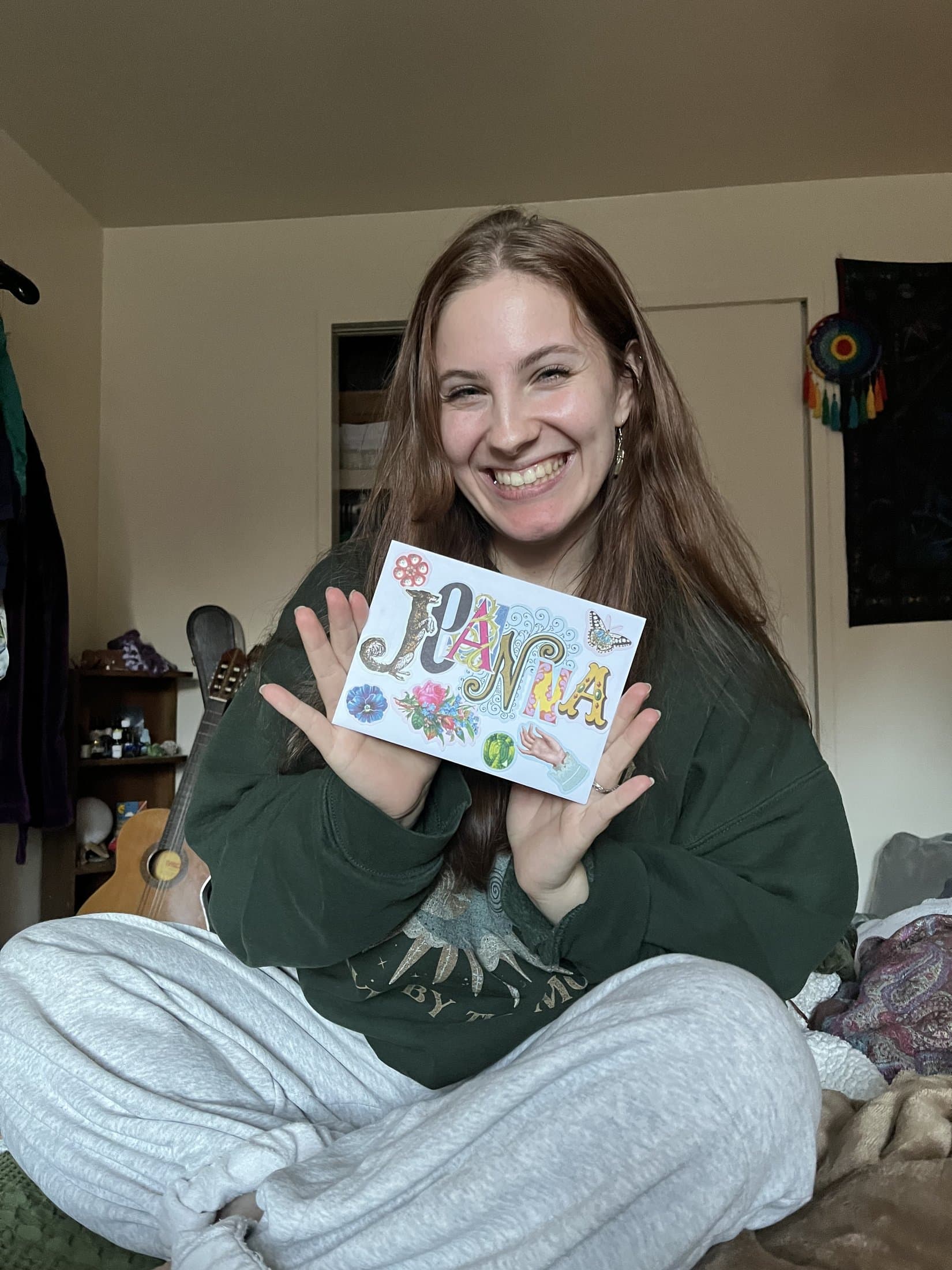 Jea laughing while holding a hand-collaged card of her name
